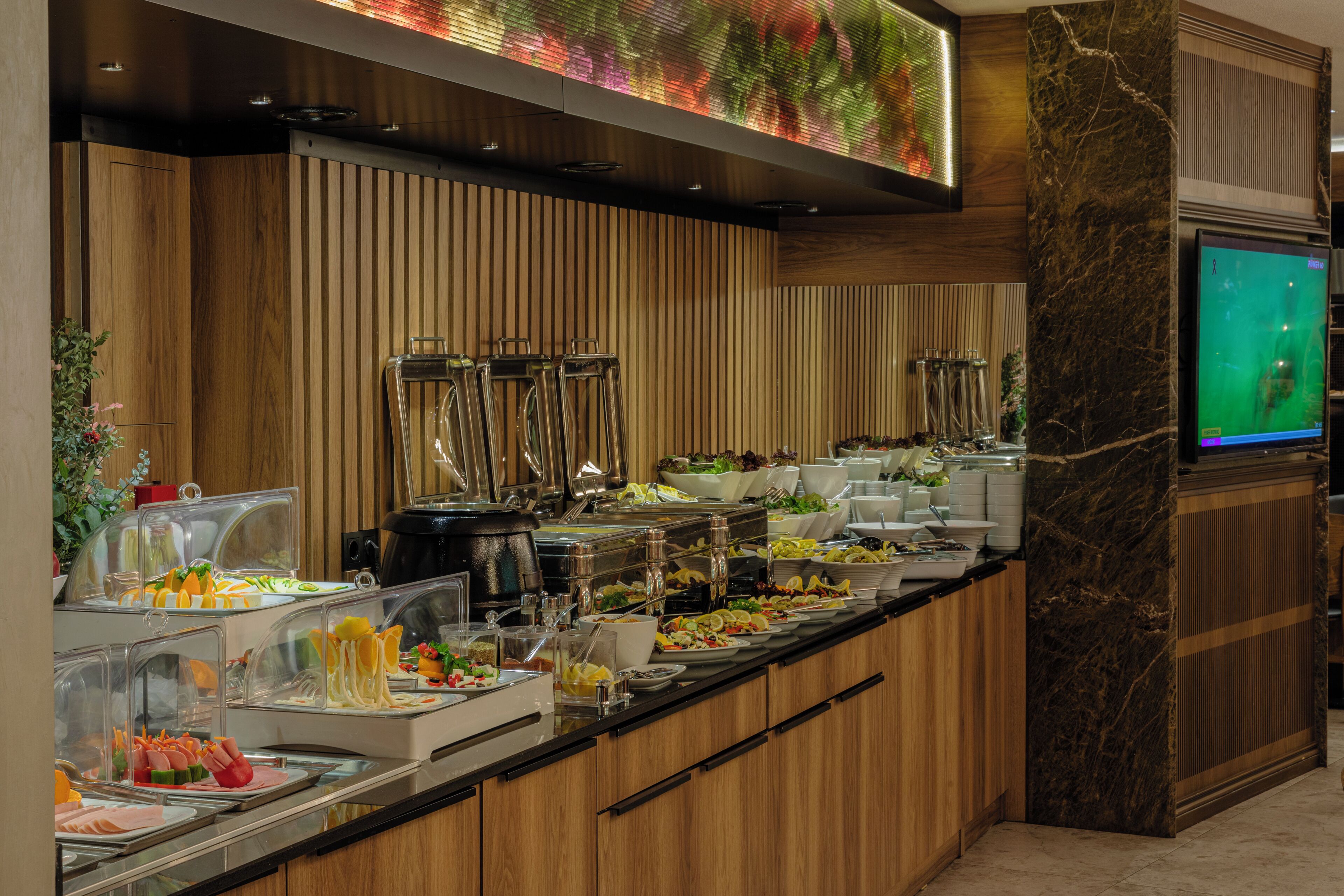 A buffet with various food items, a television, and a wooden panel wall.