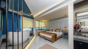 Un dormitorio moderno con una cama grande, una bañera y un área de baño separada.