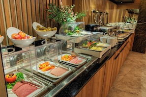 Ein Buffet mit verschiedenen Speisen, darunter Obst, Gemüse und Fleisch.