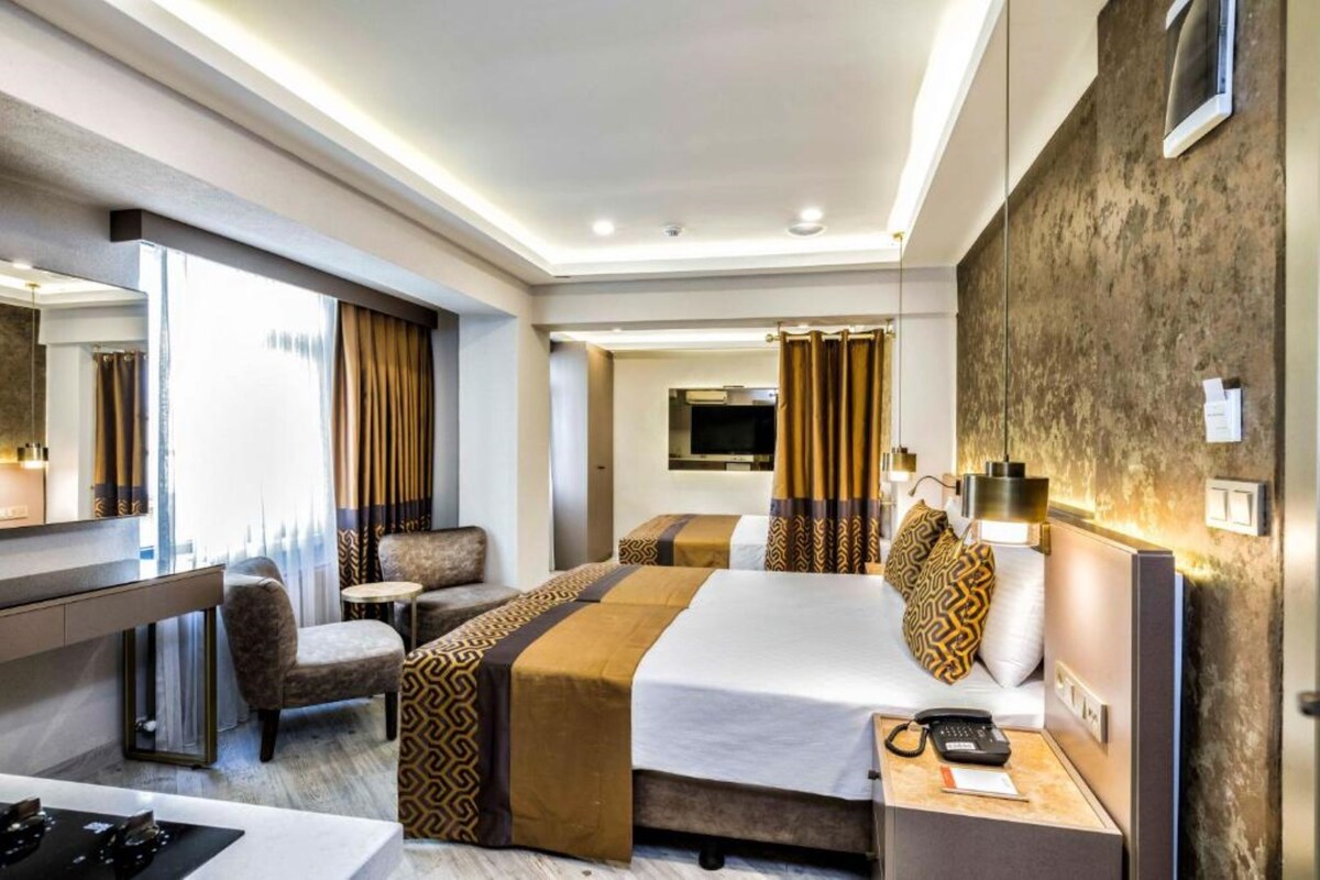 Ein Hotelzimmer mit Bett, zwei Stühlen, einem Schreibtisch, einem Fernseher und einem Badezimmer.