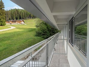 Uma varanda com vista para um edifício e uma floresta.