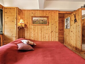 A wooden-paneled room with a bed, a lamp, and a framed picture on the wall. - Alpen Nook - Sci e Natura by Interhome (Marilleva 1400)