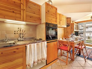 Une cuisine avec des meubles en bois, une cuisinière et un coin repas comprenant des chaises et une table.