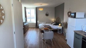 En moderne lejlighed med trægulv, spiseplads, køkken med mikroovn og en seng med udsigt.