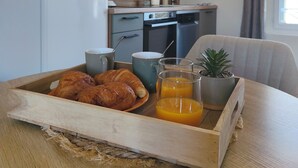 Et tekøkken med mikroovn, ovn og skabe. En bakke med croissanter og appelsinjuice står på et bord.