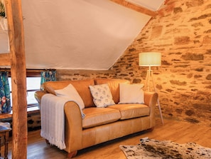 Ein gemütliches Zimmer mit Ledersofa, einer Lampe und einer Steinwand.