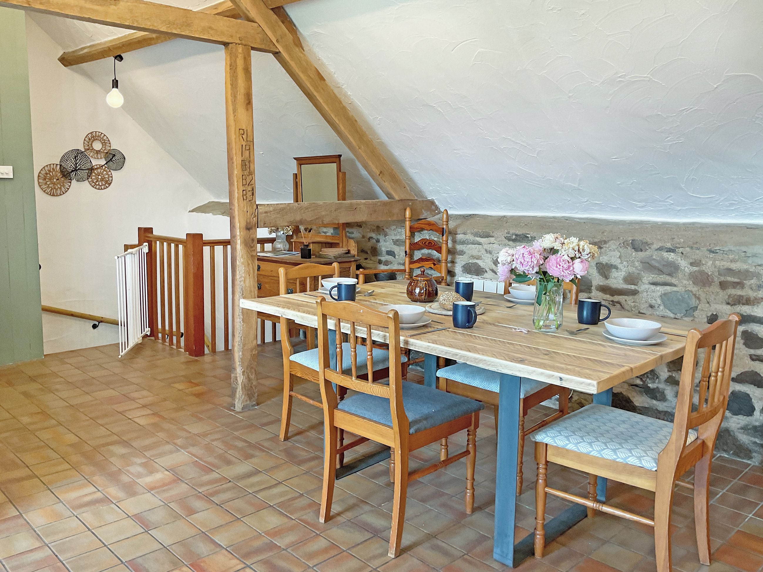 Un comedor con una mesa de madera, sillas y una pared de piedra.