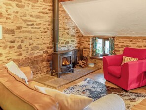 Ein gemütliches Wohnzimmer mit Steinwand, Kamin, einem roten Sofa und einer Ledercouch.