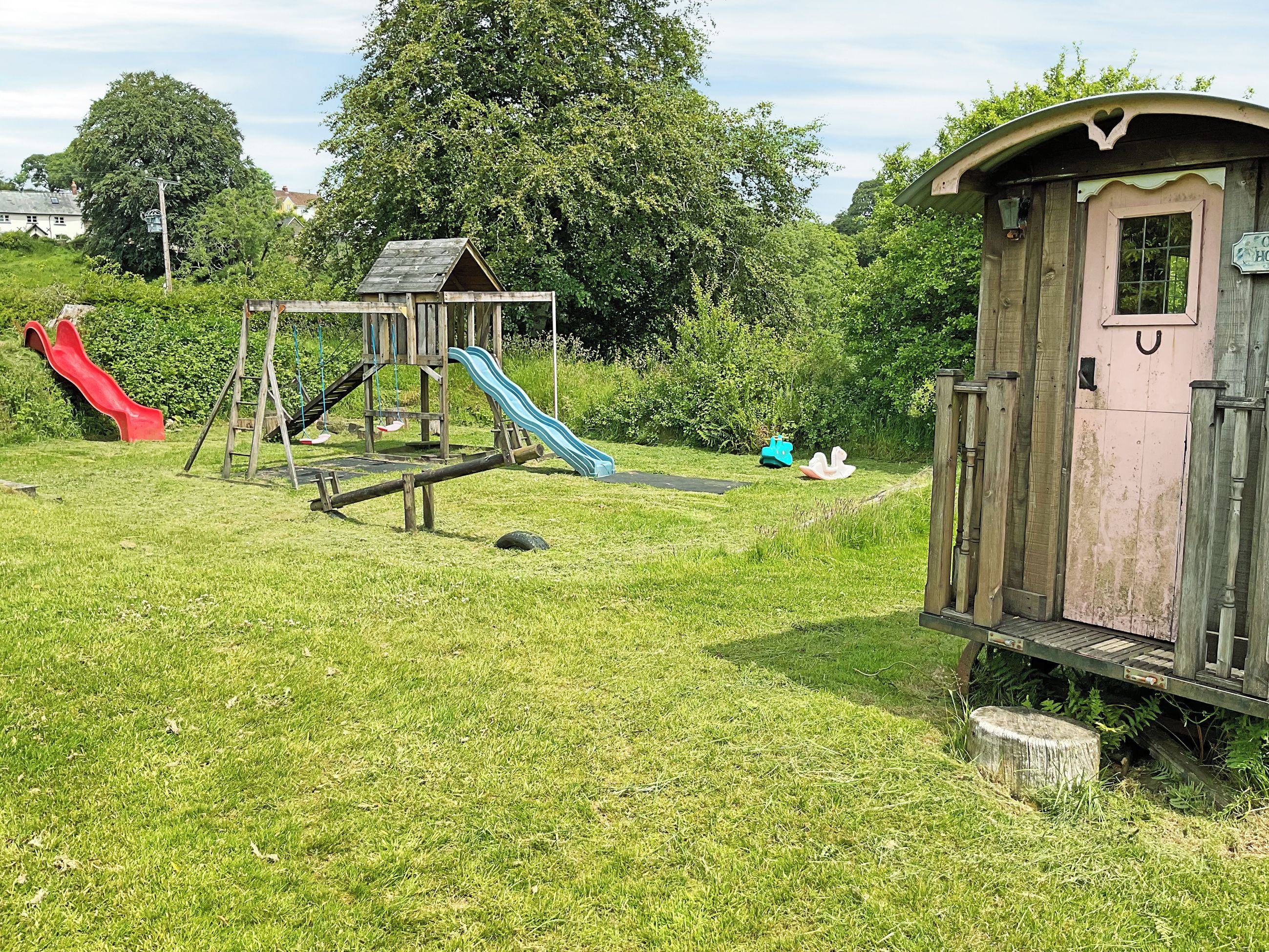 A playground with slides and swings, a small wooden structure, and a shed.