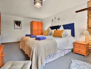 Ein Schlafzimmer mit Bett, Nachttisch, Lampe, Kleiderschrank und einem Bild an der Wand.