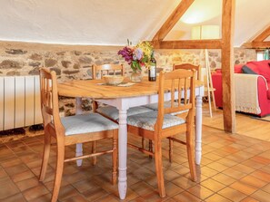 Ein Essbereich mit Holztisch und Stühlen, einer Blumenvase und einer Steinwand im Hintergrund.