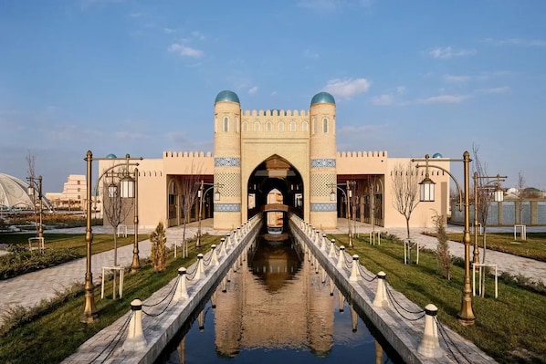 Un edificio histórico con un arco central, una vía fluvial reflectante y un diseño simétrico.