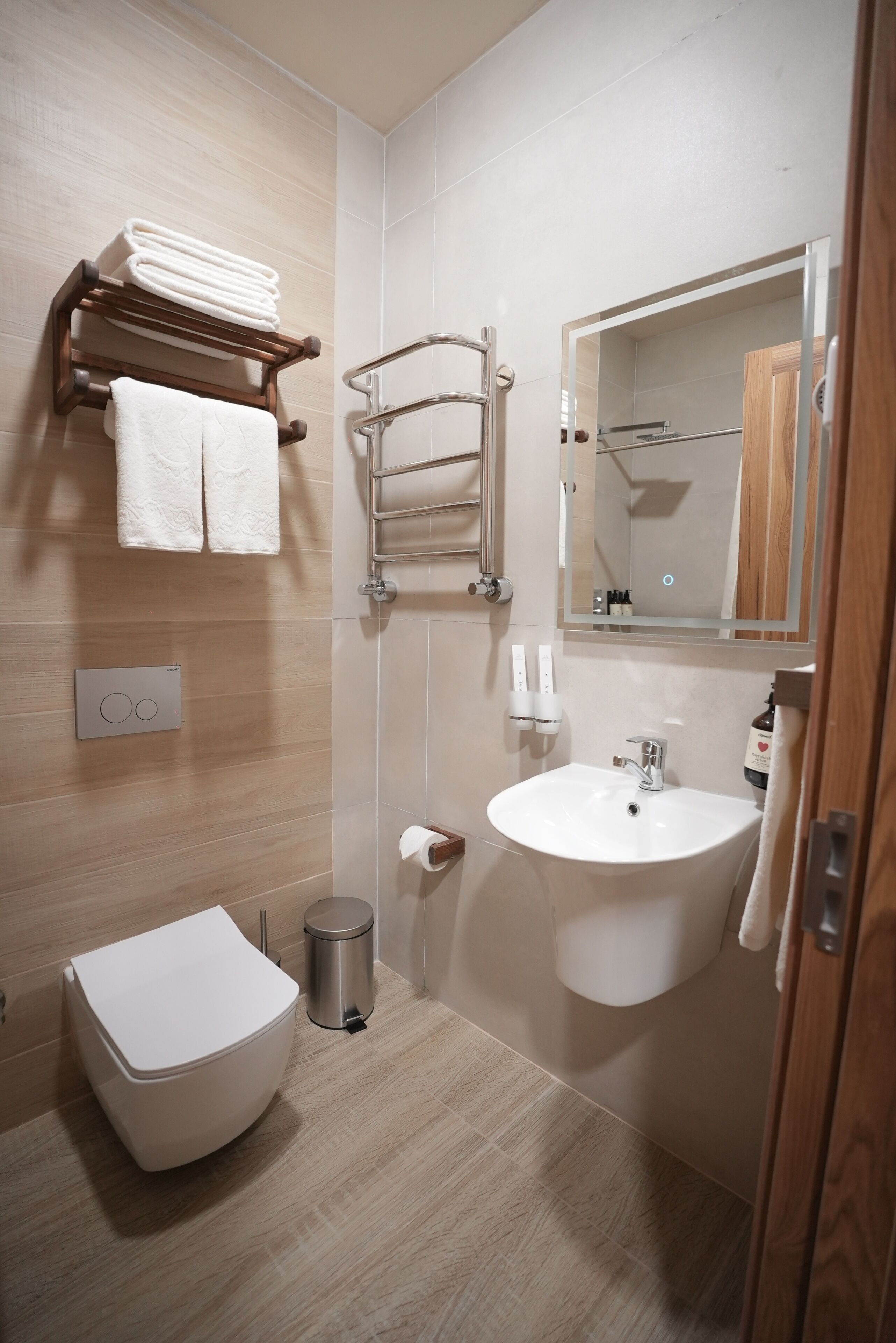 A modern bathroom with a toilet, sink, towel rack, and a mirror.