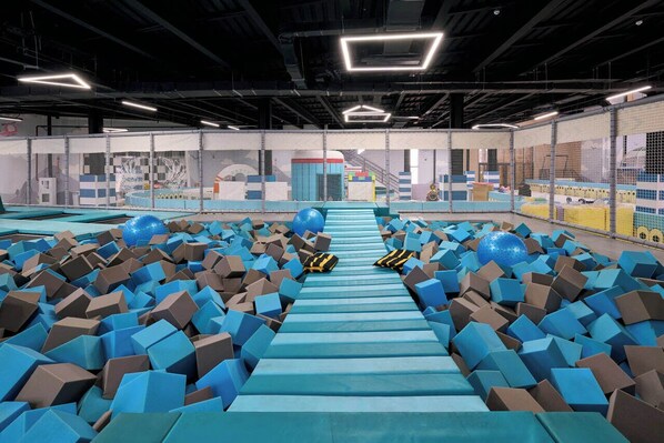 Un espace de jeux intérieur avec un chemin central bordé de blocs de mousse et de grandes sphères bleues.