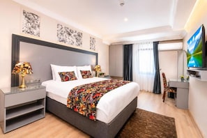 Ein modernes Hotelzimmer mit einem großen Bett, Nachttischen, einem Flachbildfernseher und Kunstwerken an den Wänden.