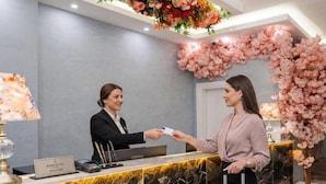 A reception desk with a marble counter, a 'Bond Hotel Welcome' sign, and a floral arrangement. - Bond Hotel Istanbul (Istanbul)