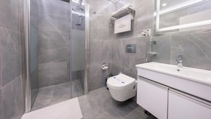 A modern bathroom with a glass-enclosed shower, a toilet, and a sink with a mirror. - Bond Hotel Istanbul (Istanbul)