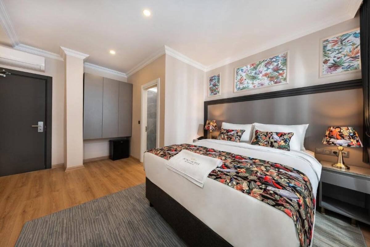 A hotel room with a large bed, a bedside table, a nightstand, and a door.