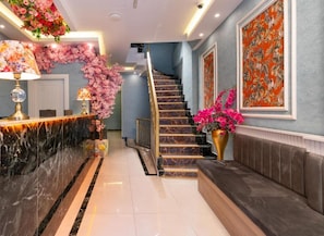 A hotel lobby with a marble reception desk, a staircase, and a seating area. - Lond Hotel (Beyoğlu)
