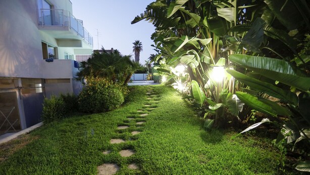 Um jardim bem cuidado com um caminho de pedra que leva à entrada de um edifício.