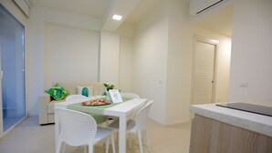 Uma sala de jantar com mesa, cadeiras, sofá e uma porta.