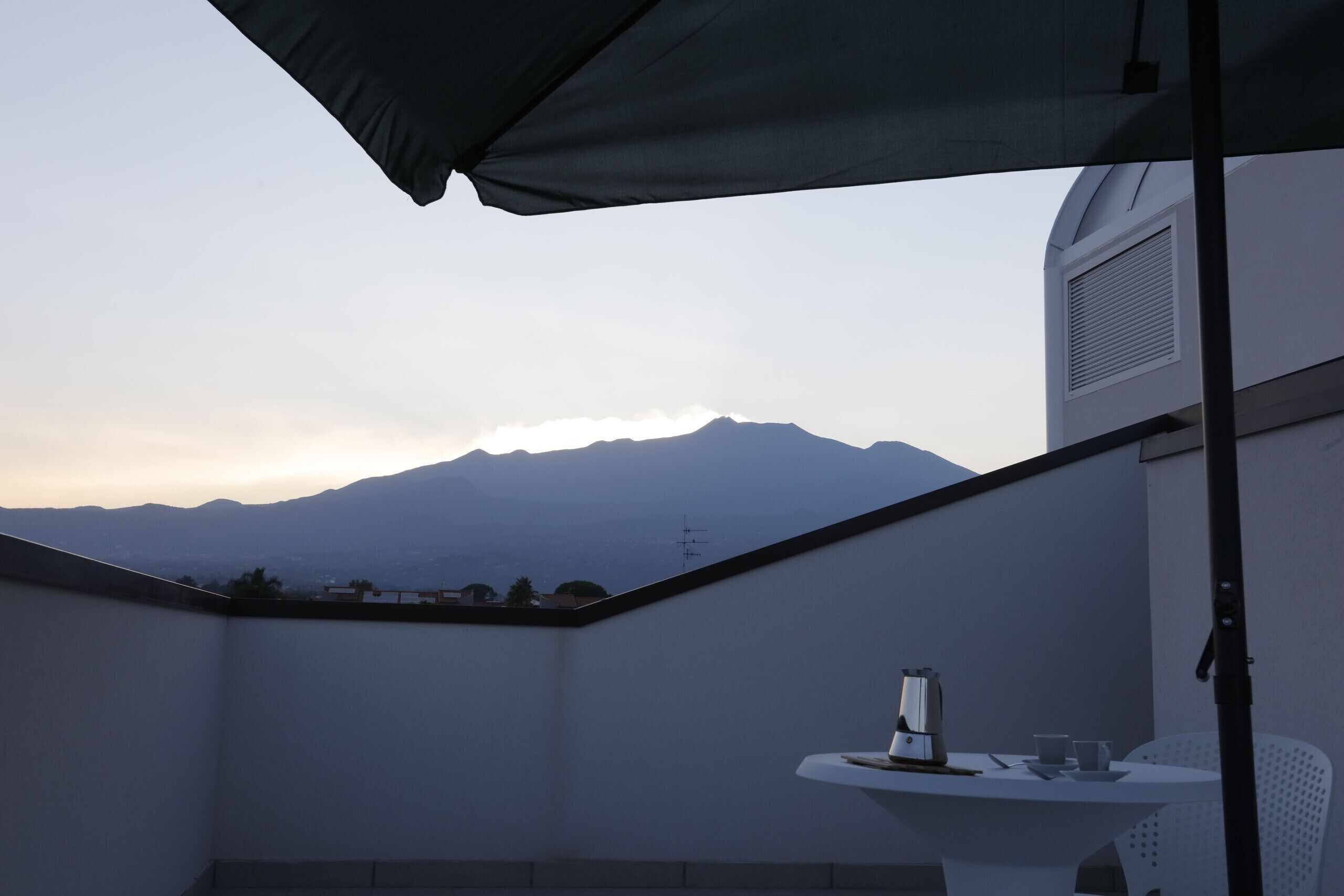 A balcony with a table, a chair, and a view of mountains.