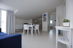 A modern, well-lit room with a dining area, a sofa, and a small table with a potted plant. - Path House - Seaview Luxury by Wonderful Italy (Riposto)