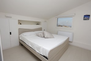Ein Schlafzimmer mit Bett, Fenster, Heizkörper und Kleiderschrank.