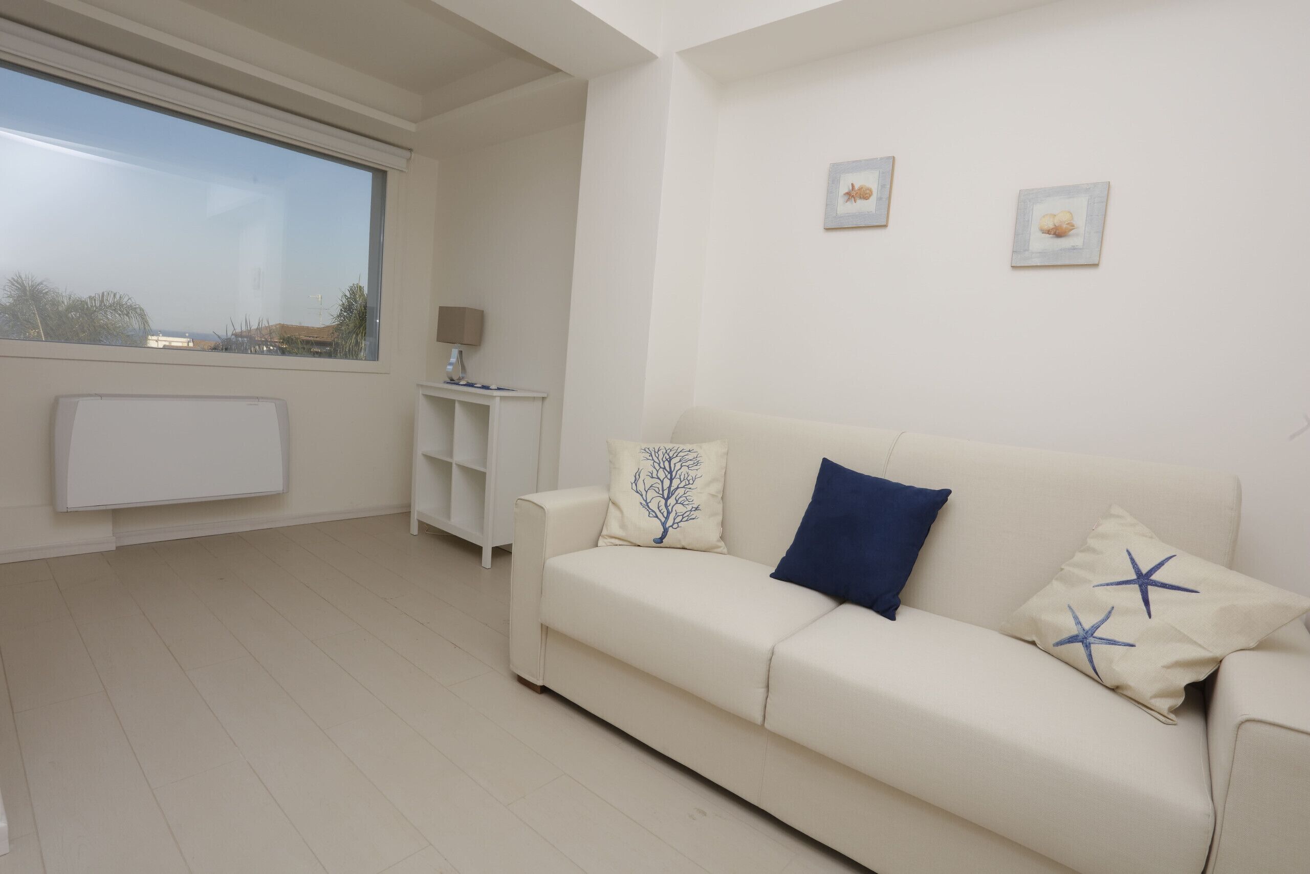 A modern living room with a white sofa, a side table, and a window with a view.