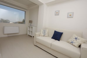A modern living room with a white sofa, a side table, and a window with a view. - Path House - Seaview Luxury by Wonderful Italy (Riposto)