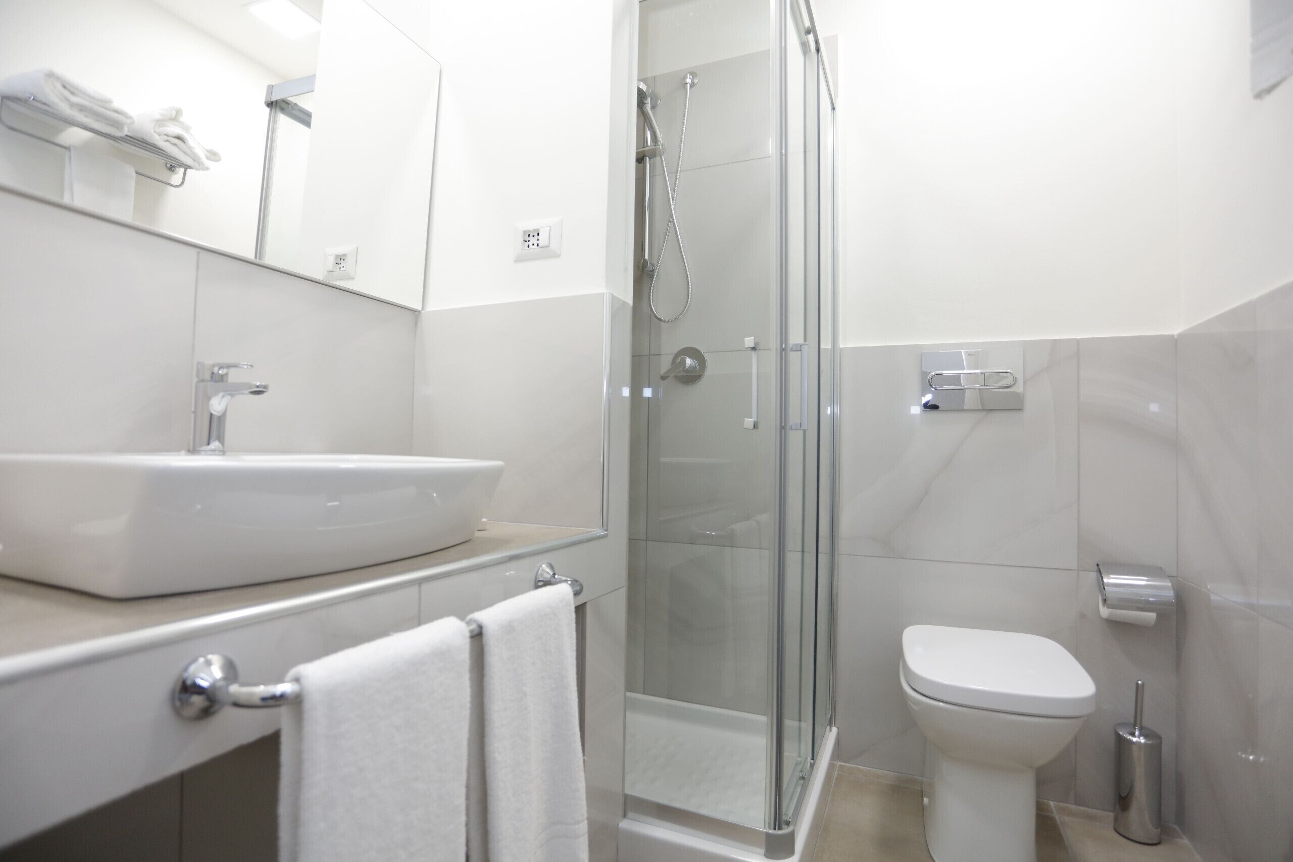 A modern bathroom with a glass-enclosed shower, a white sink, and a toilet.