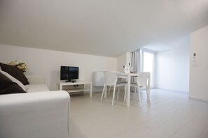 A modern living room with a white sofa, a TV, a small table, and two white chairs. - Path House - Seaview Deluxe by Wonderful Italy (Riposto)