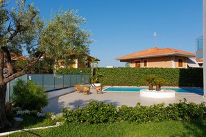 A swimming pool with lounge chairs, a palm tree, and a building with a red roof. - Path House - Seaview Deluxe by Wonderful Italy (Riposto)