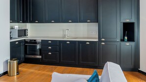 A modern kitchen with dark cabinetry, a microwave, a sink, and a trash can. - Côte d'Azur Penthouse | 45 m² in Downtown Cannes (Cannes)