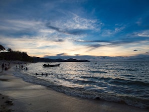 A beach with a boat, people, and a sunset. - InterContinental Penang Resort by IHG (George Town)