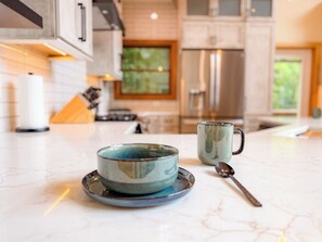 A kitchen with a bowl, mug, and spoon on the counter. - 4BR Luxury Cabin | Hot Tub, Views & 3 King Master Suites (Bryson City)