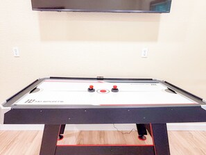 A foosball table with a 'MD Sports' logo, a television mounted above it, and a power outlet on the wall. - 4BR Luxury Cabin | Hot Tub, Views & 3 King Master Suites (Bryson City)