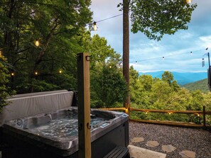 A hot tub with a wooden deck, surrounded by trees and a view of mountains. - 4BR Luxury Cabin | Hot Tub, Views & 3 King Master Suites (Bryson City)