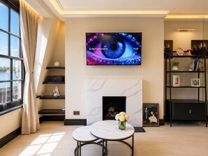 Una sala de estar moderna con televisor, chimenea, mesa de comedor y vistas al exterior.