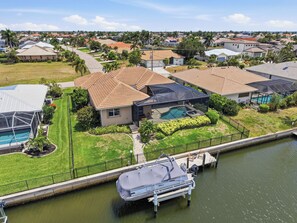 Zona residencial con casas, una piscina y un muelle con un bote.