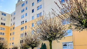 A multi-story building with a pathway lined with trees and shrubs.