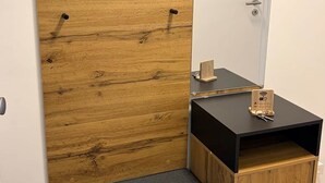 A room with a wooden cabinet, a small bench, a mirror, and a black table with a wooden tray. - Apartment da Roberto - 3 (Langenhagen)