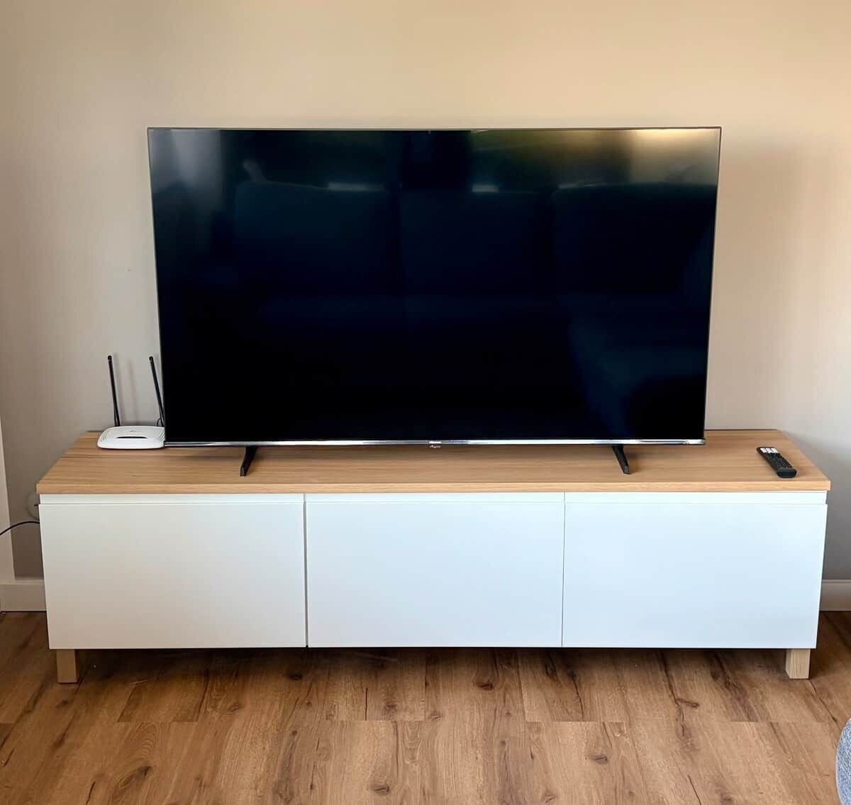A flat-screen TV on a wooden TV stand with a remote control.