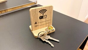 A wooden key holder with a Wi-Fi symbol, a keychain, and a small key. - Apartment da Roberto - 3 (Langenhagen)