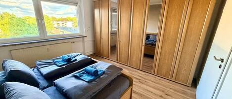 A bedroom with a bed, a wardrobe, and a window.