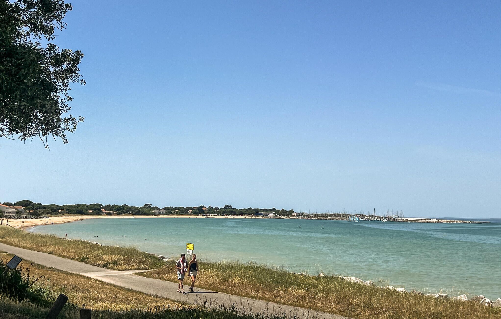 A coastal path with a clear view of the sea and distant buildings.