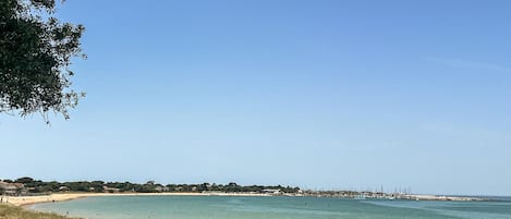 A coastal path with a clear view of the sea and distant buildings.
