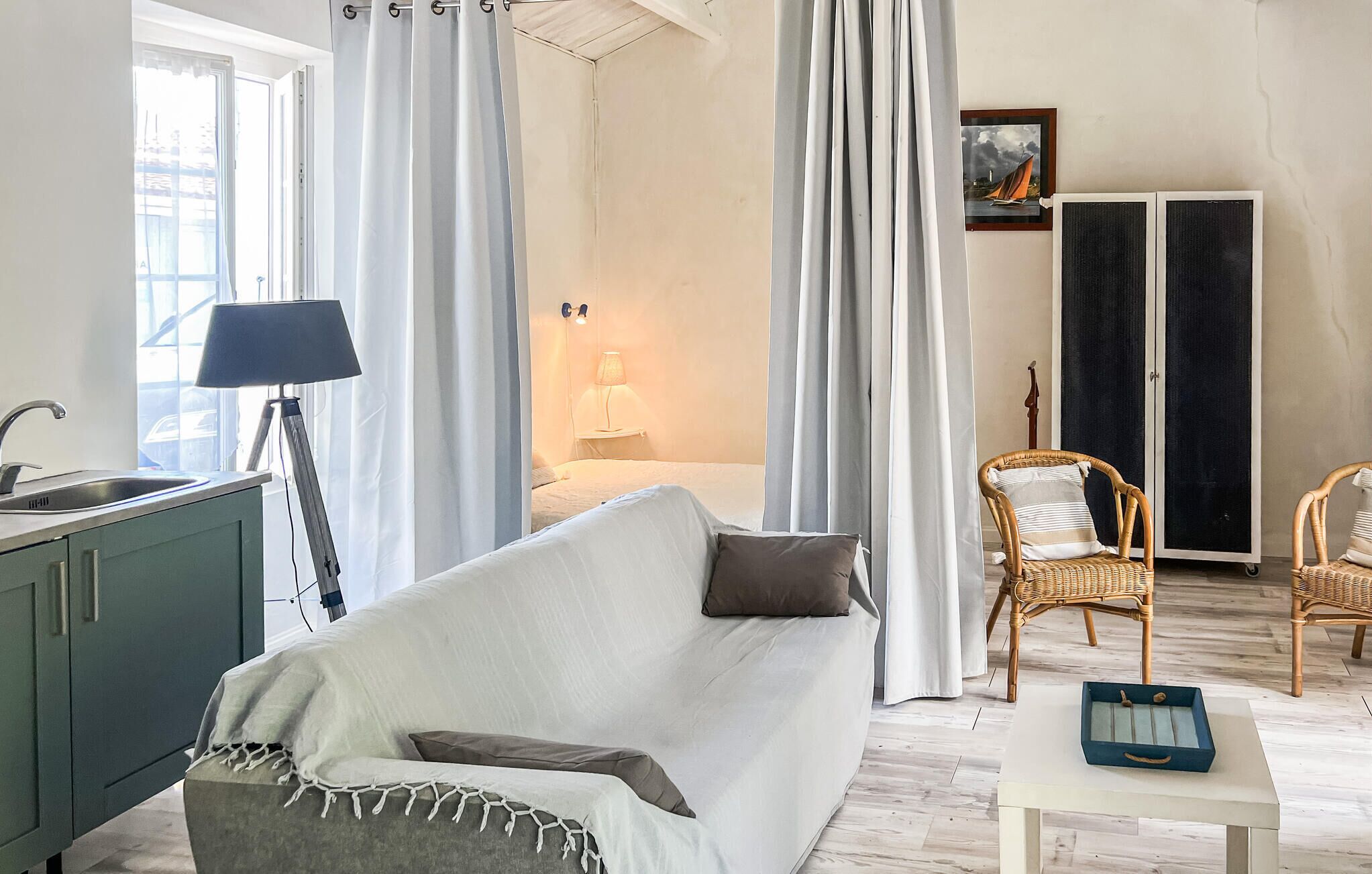 A room with a sofa, a lamp, a chair, a table, and a bed.