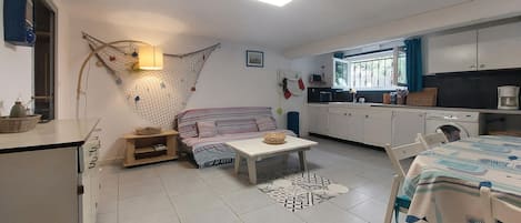 Un espacio habitable compacto con kitchenette, comedor y sofá.