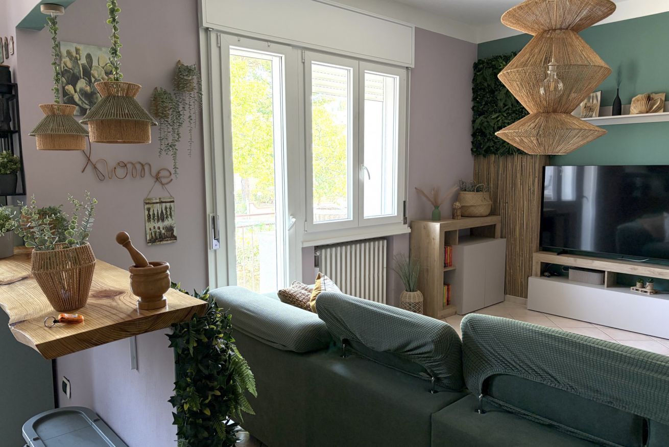 A cozy living room with a sofa, a TV, and a window with blinds.